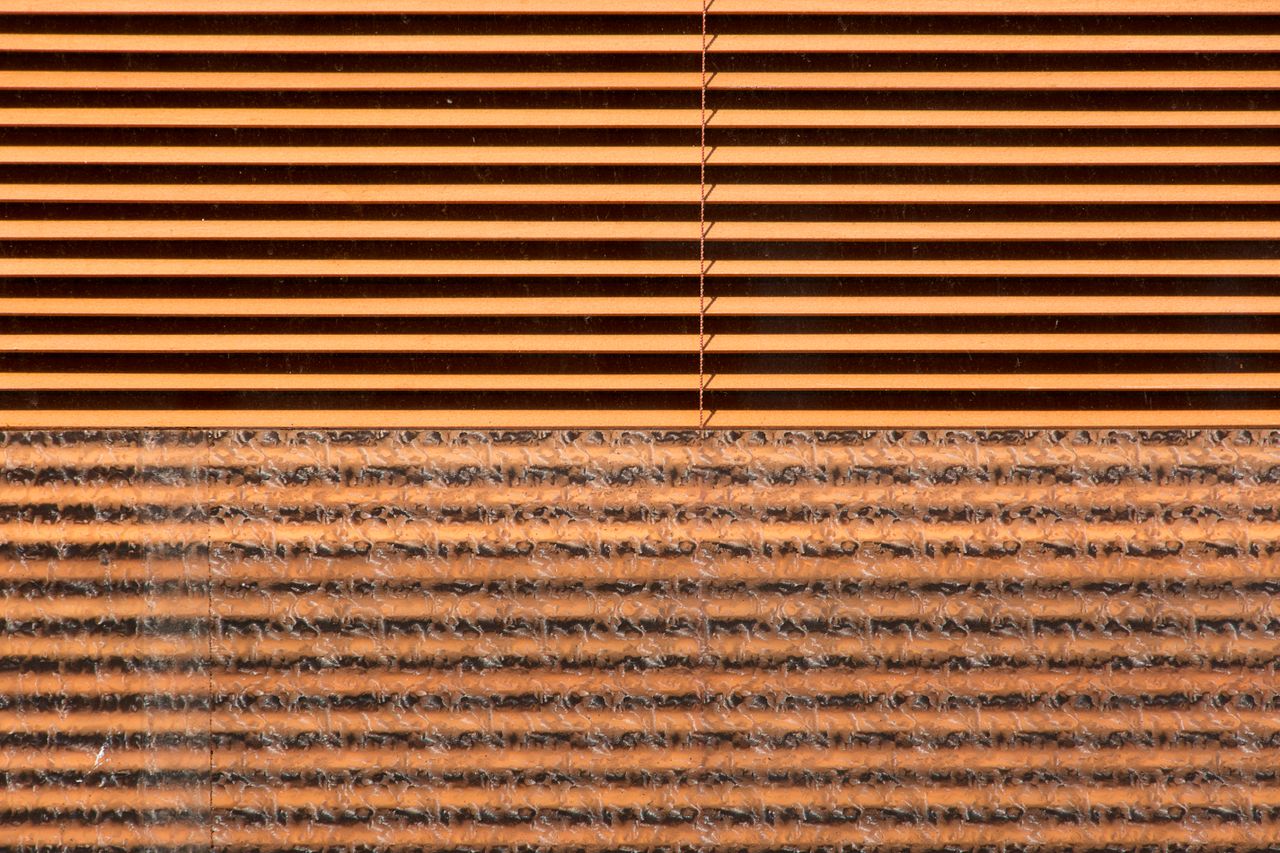 Close-up view of brown blinds with intricate pattern texture of foil and fabric.